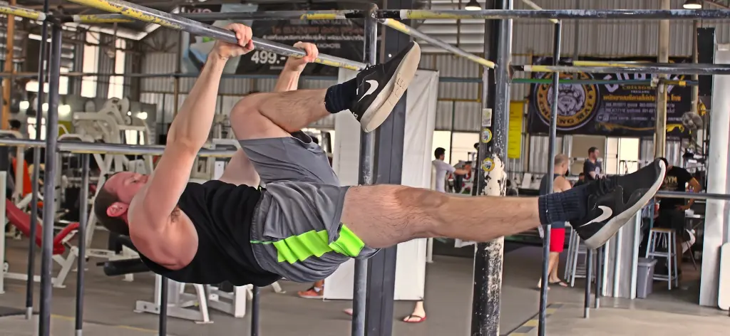 One leg tuck front lever on a pullup bar inside of a gym