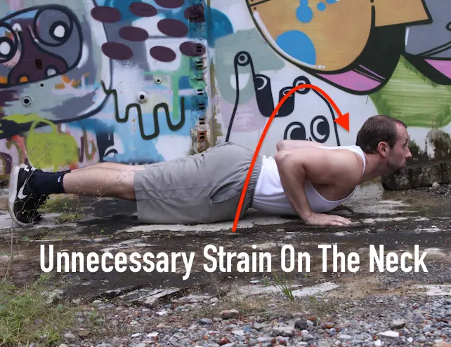 Demonstrating unnecessary neck strain in the down portion of a pushup