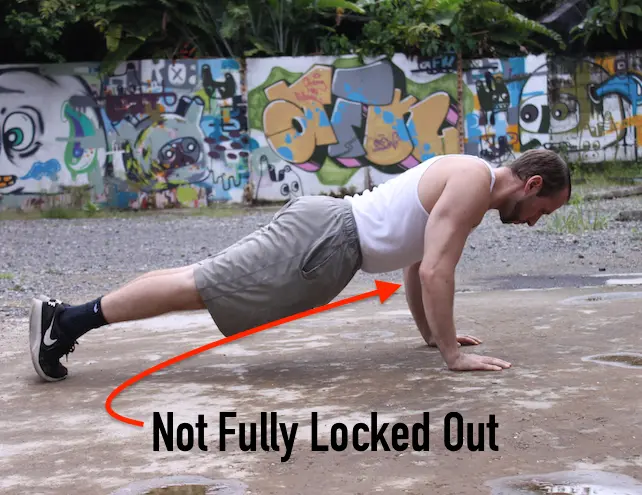 Demonstrating a partial range of motion pushup from the side, with elbows not fully locked out