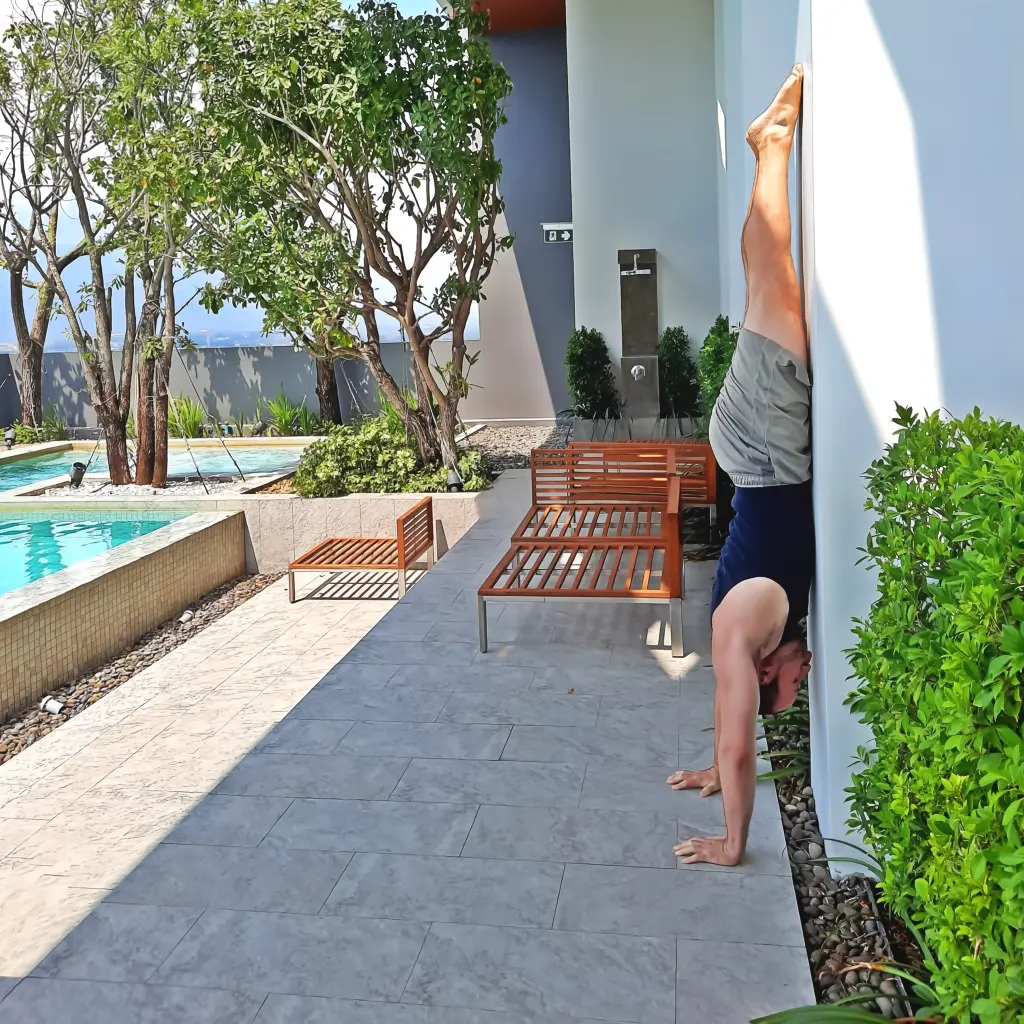 Performing a wall-assisted handstand with the chest facing toward the wall