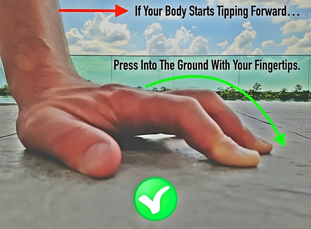 Close up of left hand showing fingertips actively pressing into the ground to counterbalance against the feet tipping forward