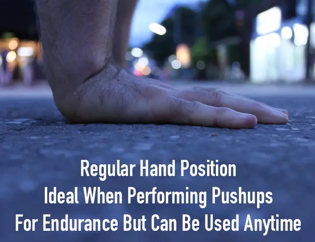A close up image of just the hands on a cement road, showing the regular hand position when doing pushups
